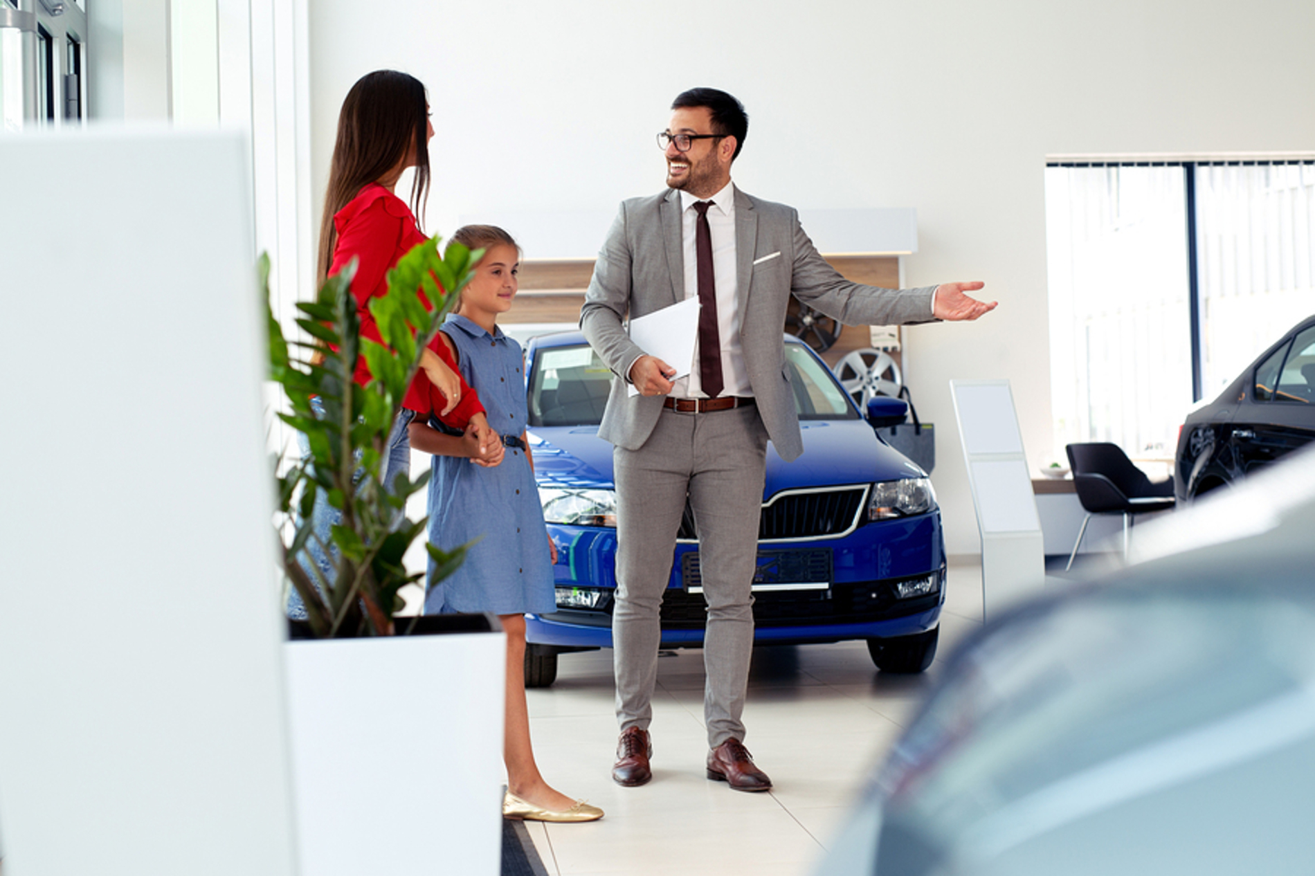 Mother and daughter talking with a car salesman.